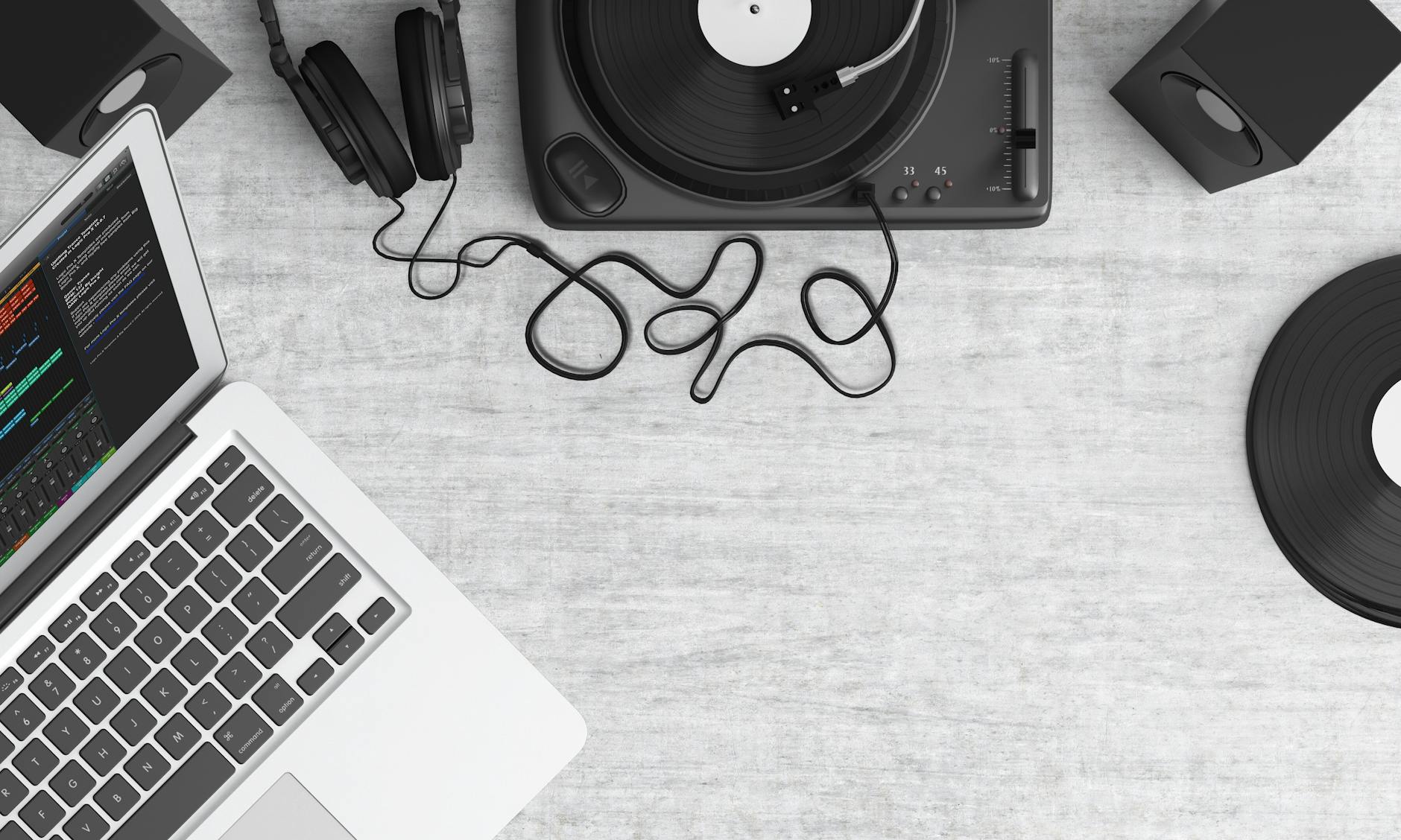 macbook pro beside black headphones on gray table