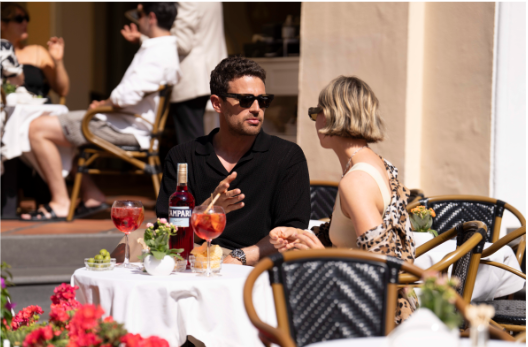 Theo James é visto aproveitando o verão europeu com Campari Spritz na mão e a esposa ao lado