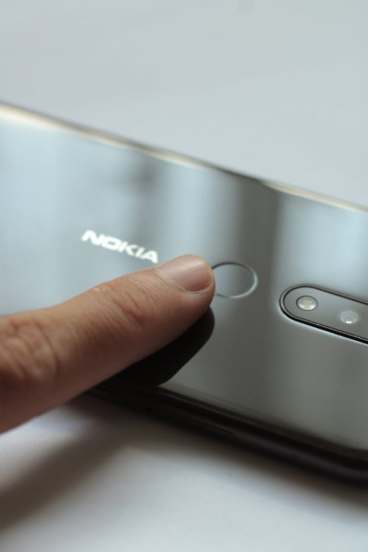 person touching the fingerprint scanner of silver nokia smartphone