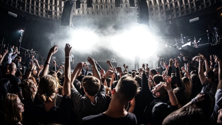 Público lotado dançando em um club com iluminação intensa durante apresentação de música eletrônica.